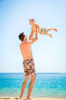 Deniz arka planda oynayan çocuk ile mutlu ebeveyn