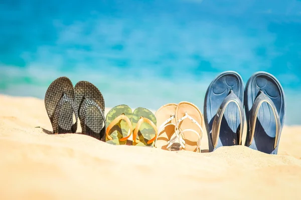 Стильные красивые тапочки в песке на морском фоне — стоковое фото