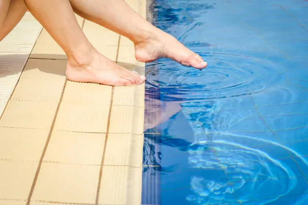 Belle gambe di una ragazza vicino a una piscina sul retro del mare — Foto Stock