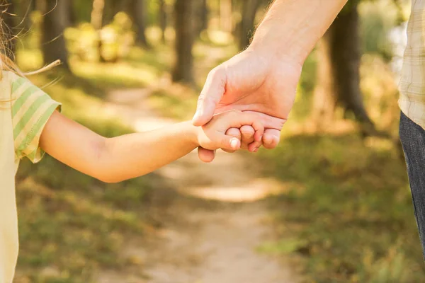 Mutlu bir geçmişi olan çocuğun elini tutan ebeveyn. — Stok fotoğraf