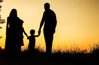 Günbatımında niteliğine mutlu bir aile silüeti 