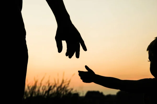 Felice padre genitore con bambino silhouette mano al tramonto in natur — Foto Stock