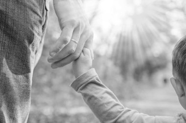 Mutlu bir geçmişi olan çocuğun elini tutan ebeveyn.