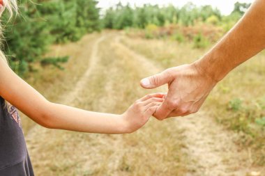 Bir parkta doğada bir ebeveyn ve çocuğun şık elleri geri