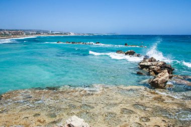 Arka planda dalgalar olan güzel bir sahil.