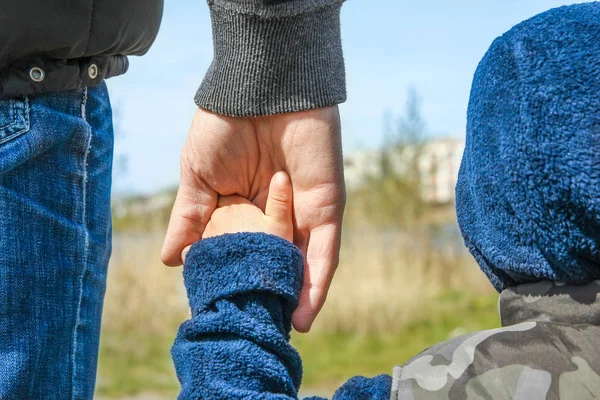 Les mains élégantes d'un parent et d'un enfant dans la nature dans un parc retour — Photo