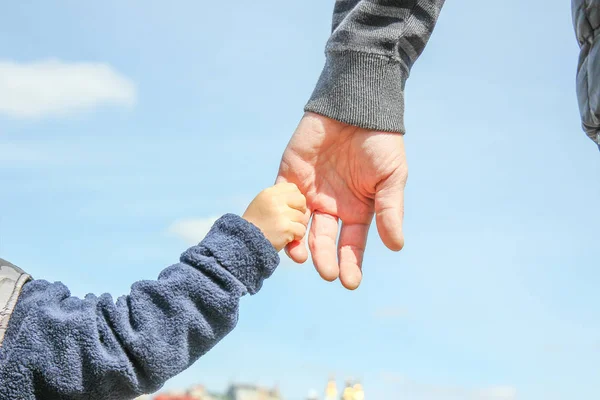 Mãos elegantes de um pai e uma criança na natureza em um parque atrás — Fotografia de Stock