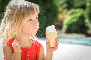 Parkın doğasında dondurma yiyen mutlu çocuk.