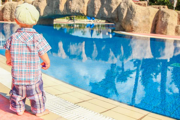 Ett lyckligt barn leker vid poolen på naturen vid havet — Stockfoto