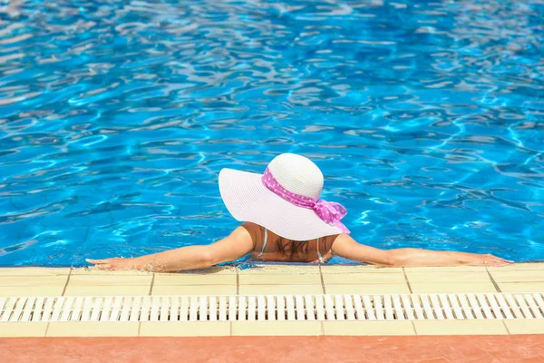 Gelukkig meisje in een hoed bij het zwembad op de aard van de zee kust — Stockfoto