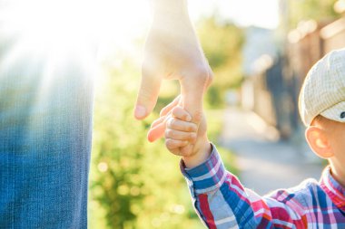 Mutlu bir geçmişi olan çocuğun elini tutan ebeveyn.