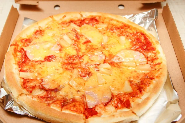 Hot pizza slice with melting cheese on a rustic wooden table — Stock Photo, Image