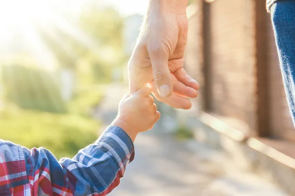 A szülő boldog háttérrel fogja a gyermek kezét — Stock Fotó