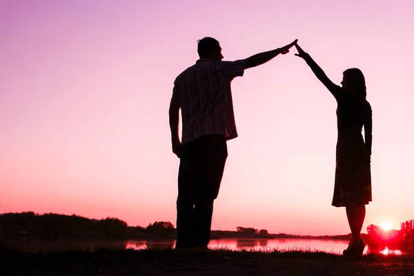 Happy couple silhouette against a sunset romance — Stock Photo, Image