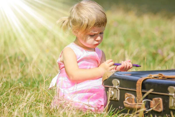 Bébé fille heureuse avec une valise à l'extérieur au parc — Photo