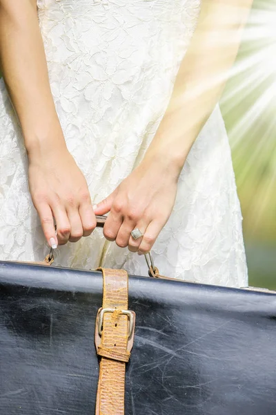 Stylish and beautiful in the hands of a suitcase outdoors in the — Stock Photo, Image
