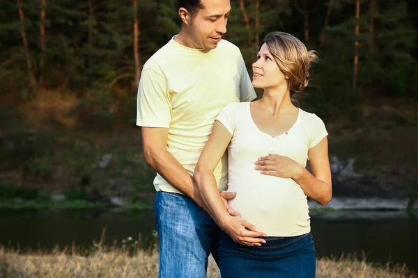 Gelukkige man met vrouw zwanger op de natuur in de zomer — Stockfoto