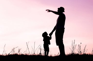 Çocuklu mutlu bir ebeveyn yaz siluetinde oynuyor.