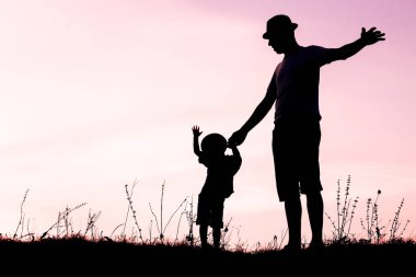 Çocuklu mutlu bir ebeveyn yaz siluetinde oynuyor.