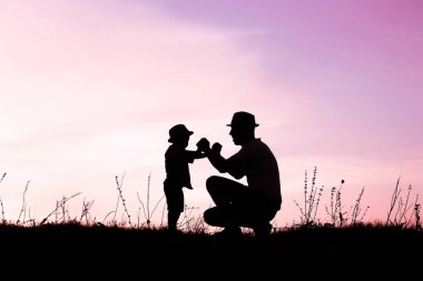 Çocuklu mutlu bir ebeveyn yaz siluetinde oynuyor.