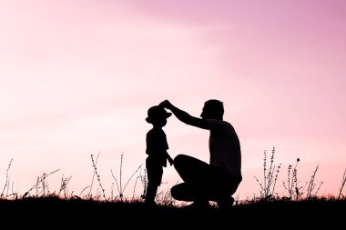 Çocuklu mutlu bir ebeveyn yaz siluetinde oynuyor.