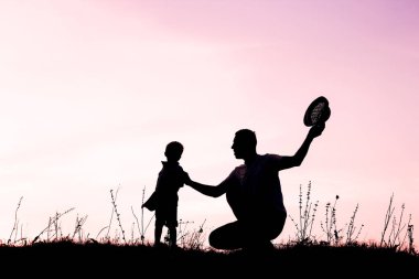 Çocuklu mutlu bir ebeveyn yaz siluetinde oynuyor.