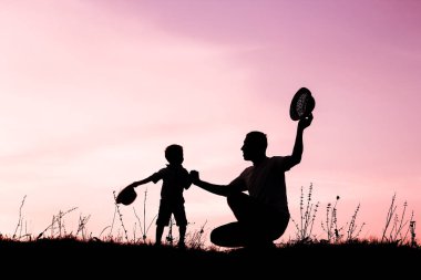 Çocuklu mutlu bir ebeveyn yaz siluetinde oynuyor.