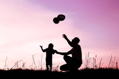 Çocuklu mutlu bir ebeveyn yaz siluetinde oynuyor.