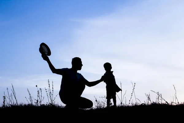 Genitore felice con bambini che giocano sulla silhouette estiva della natura — Foto Stock