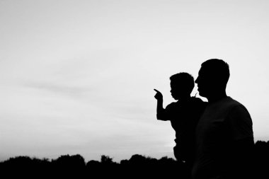 Çocuklu mutlu bir ebeveyn yaz siluetinde oynuyor.