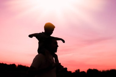 Çocuklu mutlu bir ebeveyn yaz siluetinde oynuyor.