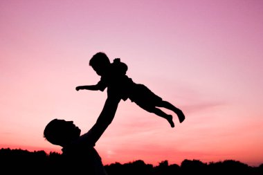 Çocuklu mutlu bir ebeveyn yaz siluetinde oynuyor.