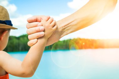 deniz tarafından bir parkta doğada bir ebeveyn ve çocuk elleri