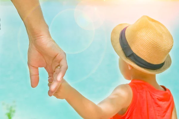 Mani di un genitore e di un bambino nella natura in un parco in riva al mare — Foto Stock