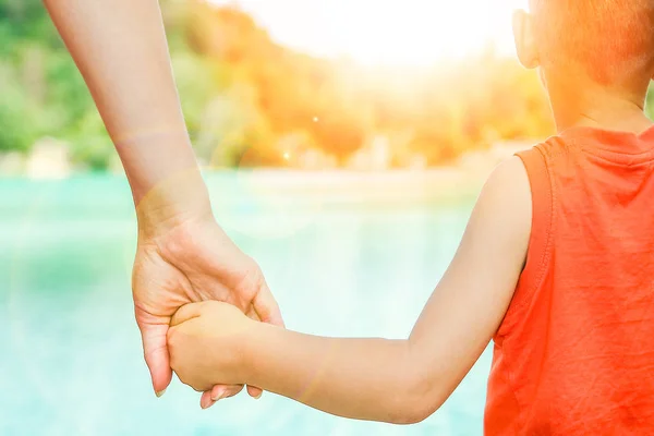 Mani di un genitore e di un bambino nella natura in un parco in riva al mare — Foto Stock