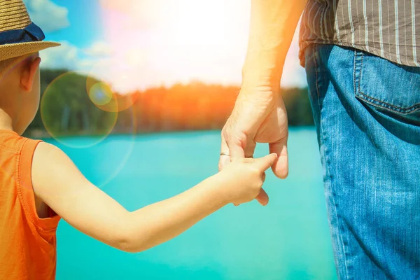 Mains d'un parent et d'un enfant dans la nature dans un parc au bord de la mer — Photo