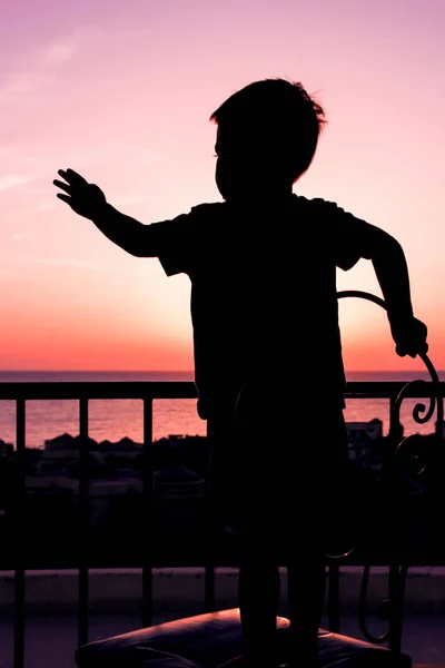 Счастливый ребенок во время силуэта морского фона — стоковое фото