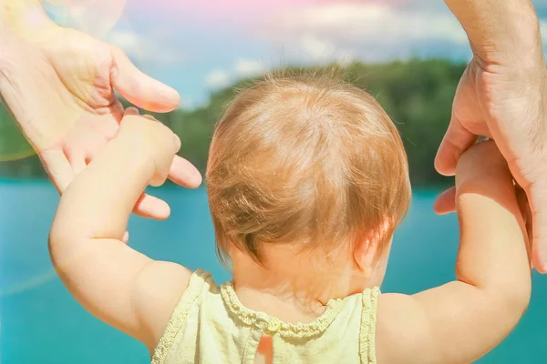 Mani di un genitore e di un bambino nella natura in un parco in riva al mare — Foto Stock