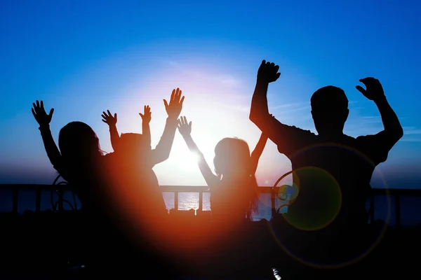 Familia feliz en el amanecer del fondo de la silueta del mar — Foto de Stock