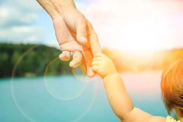 Mani di un genitore e di un bambino nella natura in un parco in riva al mare — Foto Stock