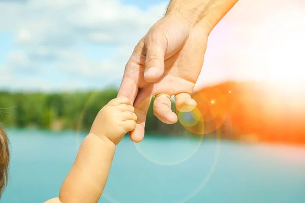 Mani di un genitore e di un bambino nella natura in un parco in riva al mare — Foto Stock