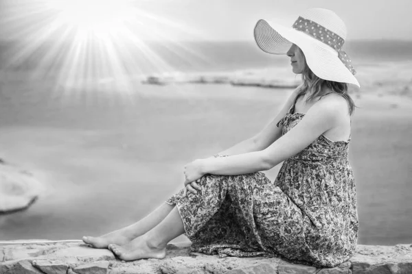 아름다운 모자를 쓰고 해변 배경에 앉은 스타일의 아름다운 소녀 — 스톡 사진