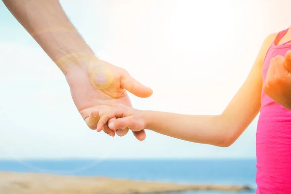 Piękne ręce rodzica i dziecka na tle morza — Zdjęcie stockowe