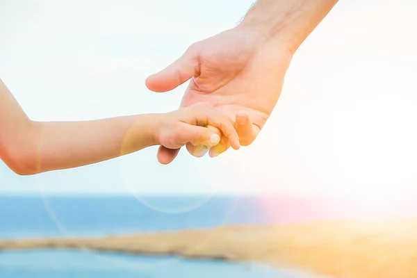 Prachtige handen van ouder en kind op zee achtergrond — Stockfoto