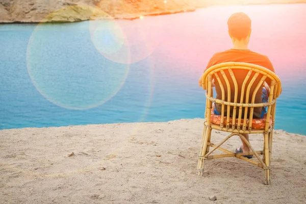 Cara feliz sentado em um banquinho junto ao fundo do mar na natureza — Fotografia de Stock