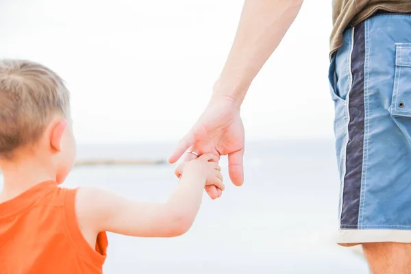 Beautiful hands of parent and child on sea background — Stock Photo, Image