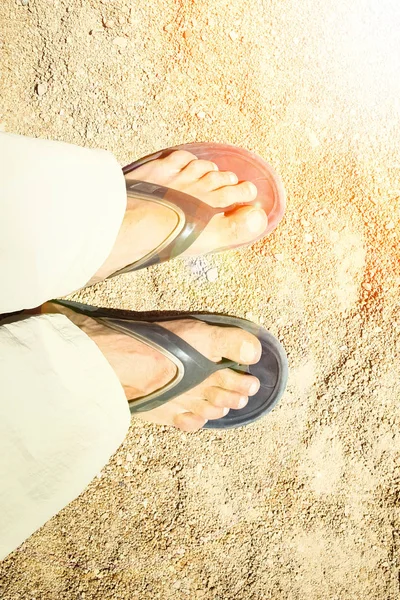 Pernas bonitas em chinelos no fundo de areia — Fotografia de Stock