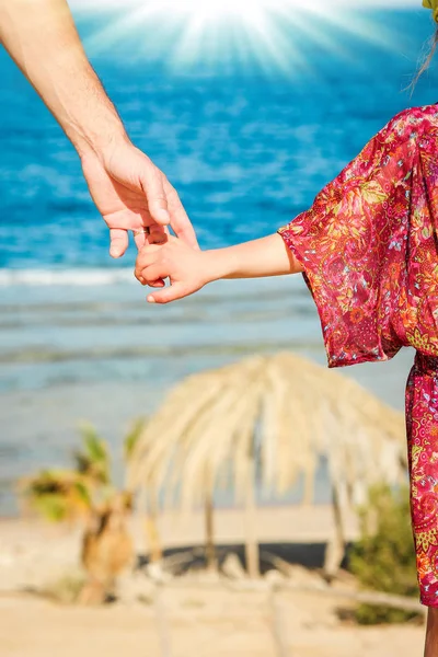 Beautiful hands of parent and child on sea background — Stock Photo, Image