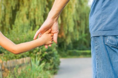 Mutlu bir geçmişi olan çocuğun elini tutan ebeveyn.