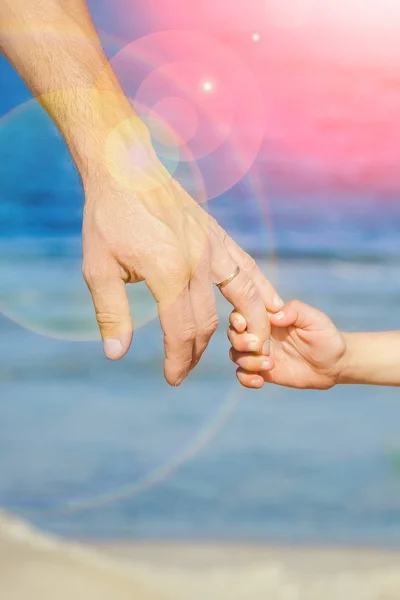 Beautiful hands of parent and child on sea background — Stock Photo, Image